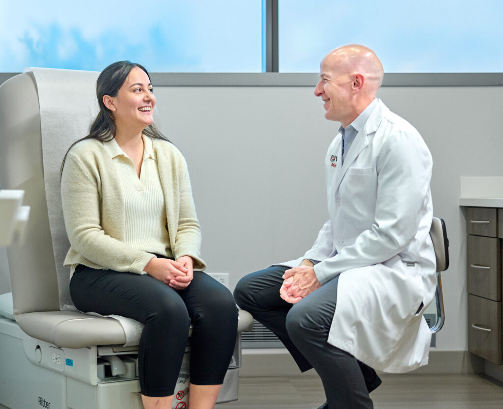 Physician and patient conversing happily in a patient exam room