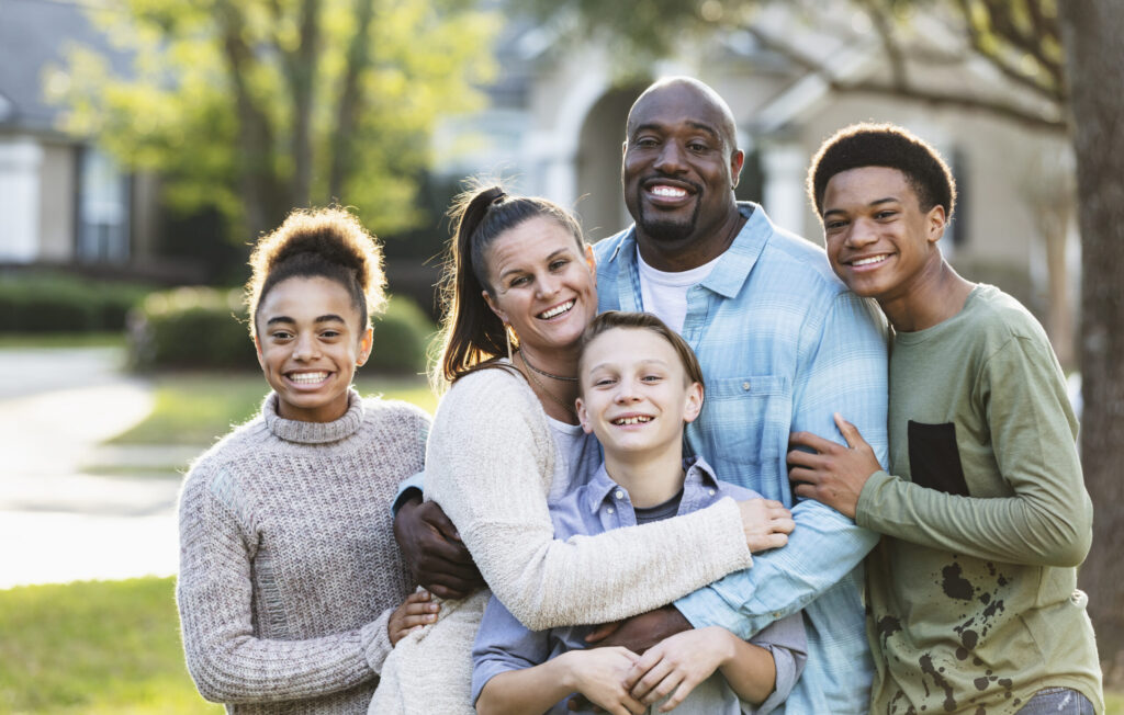 a mixed-race family portrait with the family all hugging the child