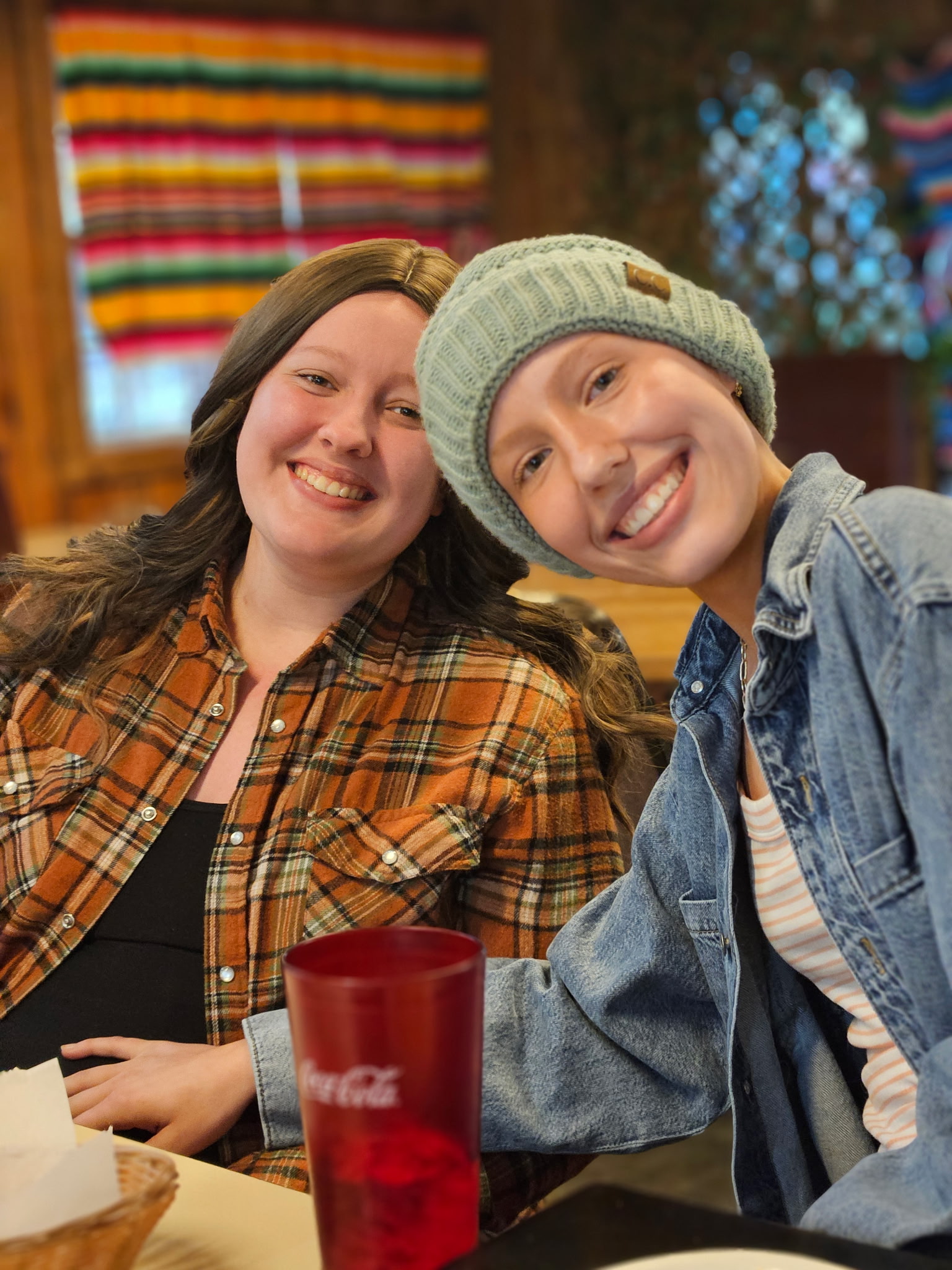 Two women at a restaurant lean towards each other and smile