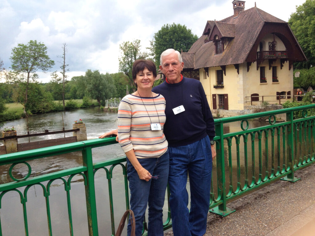 a portrait of a wife and husband over a bridge with a river behind them