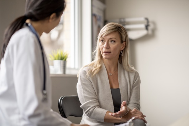 A middle aged woman sits down with her doctor