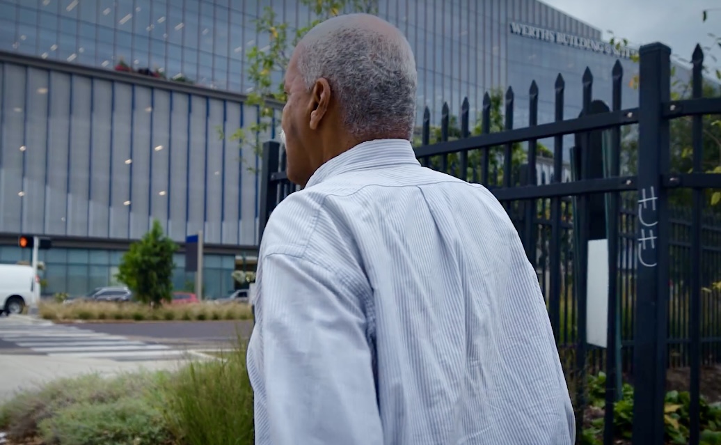 Man in blue shirt faces large building