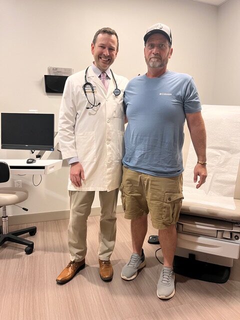 Photograph of Rick Sparrow standing alongside Peter Oppelt, MD, in a medical office setting.