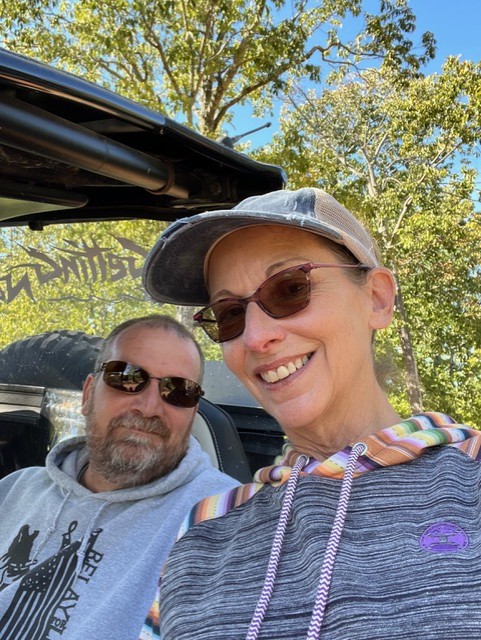 Photograph of Rick and Dianna Sparrow smiling together outdoors while seated in a UTV.